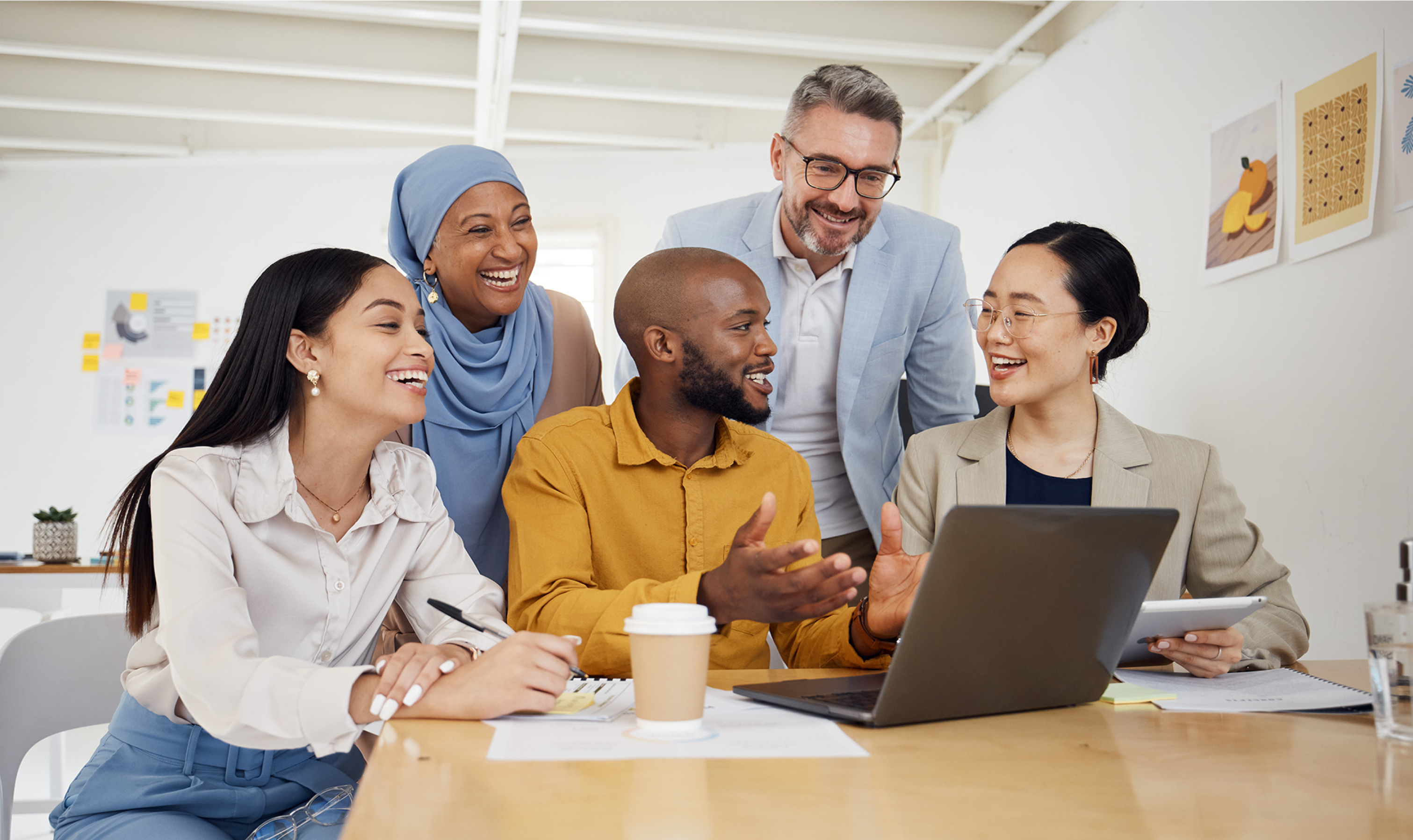 group of coworkers smiling while around a laptop