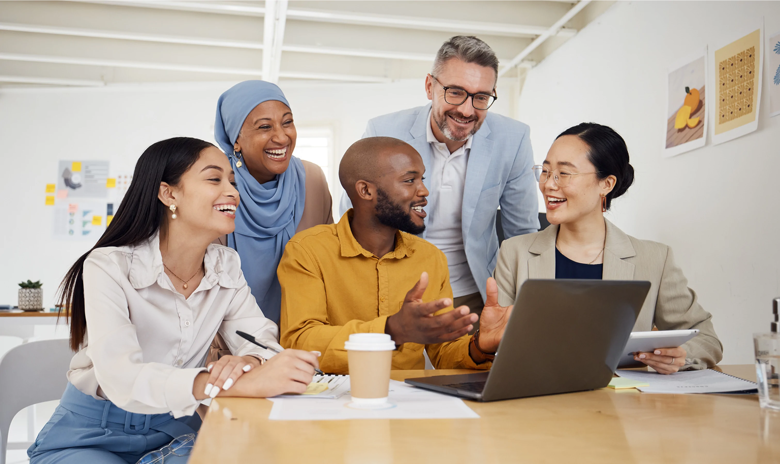 group of coworkers smiling while around a laptop